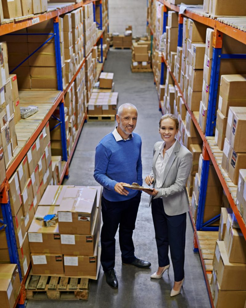 Order status Shipped. Portrait of two managers looking at stock in a large warehouse